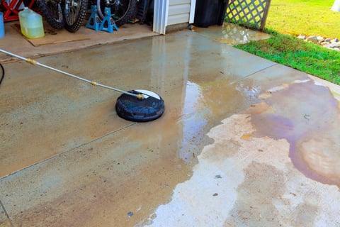 Driveway is being cleaned with high pressure washer, creating shiny surface
