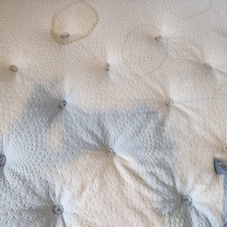 Cream upholstered fabric with tufted button detailing in a quilted pattern