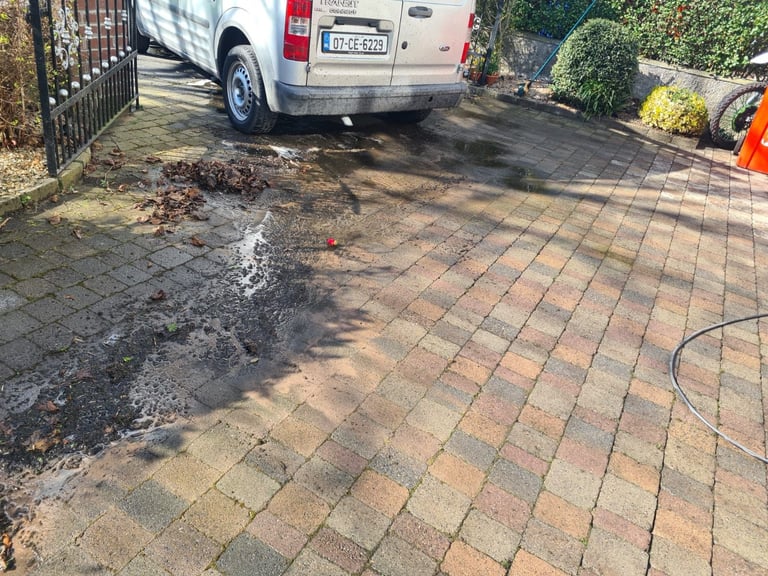 Driveway being pressure washed with wet brick pavers and white van parked in background