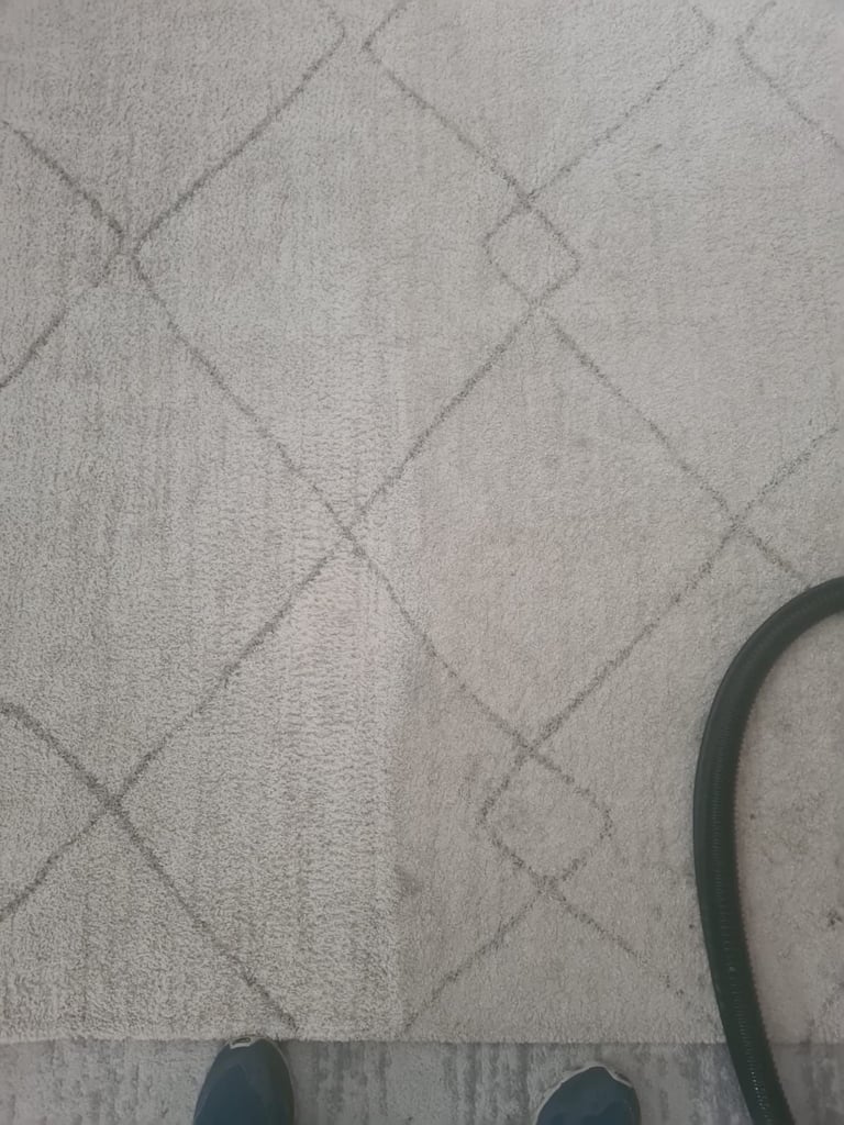 Close-up of beige quilted fabric with diamond pattern and partial view of dark hose or cord in corner