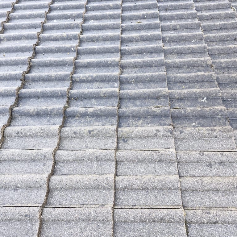 Close-up of gray concrete roof tiles arranged in overlapping rows with visible mortar joints