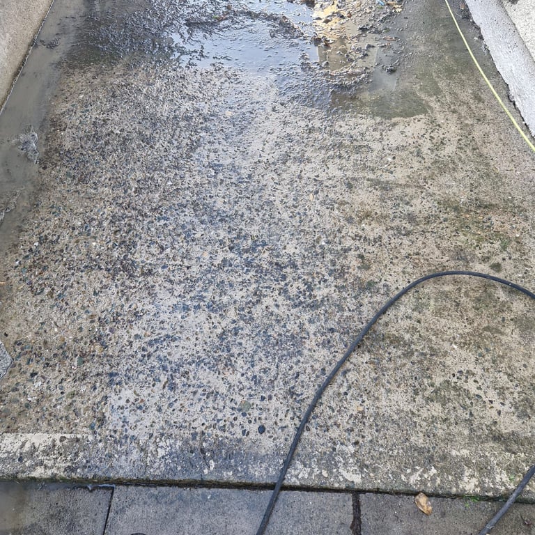Overhead view of a dirty concrete surface with a black hose lying across it