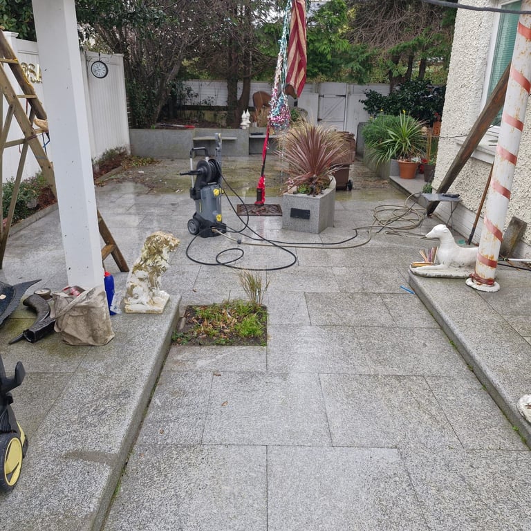 Coiled garden hoses on a paved patio surrounded by potted plants and stucco-walled buildings