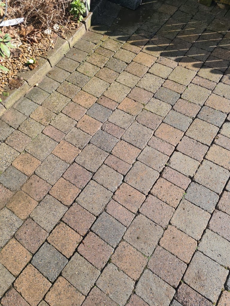 Brown and tan patterned brick pavers arranged in an alternating herringbone design on a patio or walkway