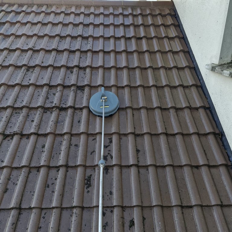 Satellite dish mounted on brown tiled roof with white wall visible in corner